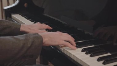 Müzik okulunda piyano çalan tanınmayan erkek ellerinin yavaş yavaş yakın çekimi.