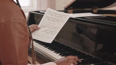 Müzik okulunda siyah piyanoda notalar çalan Afrikalı-Amerikalı kadın müzisyen yavaşladı.