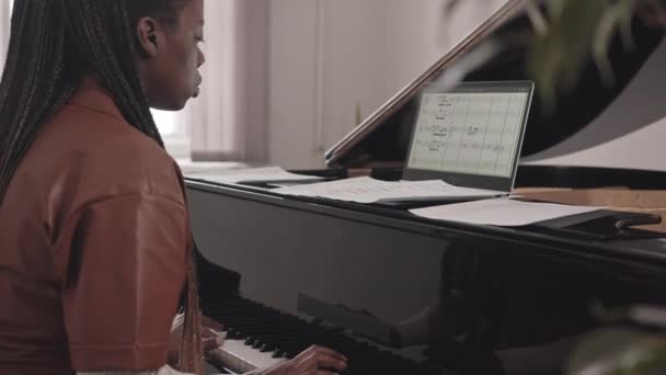 若い黒の女性の中低速タブレットPc上の音楽ノートの写真を使用してグランドピアノを再生することを学ぶ — ストック動画