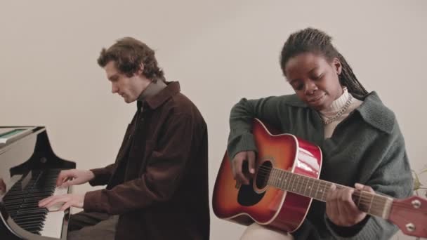 中等速度的有才华的跨种族音乐家夫妇一起在室内弹钢琴和吉他 — 图库视频影像