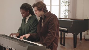 Erkek öğretmenle müzik dersinde klavye çalmayı öğrenen Afro-Amerikalı genç bir kadının orta yavaşlığı.