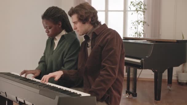 若いアフリカ系アメリカ人女性の中低速男性教師と音楽のレッスンでキーボードを再生することを学ぶ — ストック動画