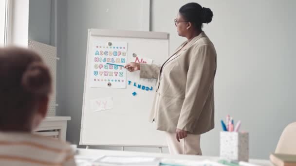 Lentitud Media Maestra Afroamericana Pie Pizarra Blanca Apuntando Las Letras — Vídeo de stock