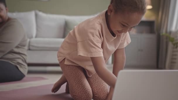 Slowmoのアフリカ系アメリカ人5歳の女の子オープンビデオレッスン上のラップトップしばらくトレーニングとともに自宅で彼女の体正の母親 — ストック動画