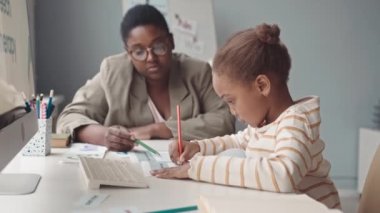 5 yaşındaki Afro-Amerikan kız ve bayan öğretmenin modern beyaz sınıfında konuşma terapisi dersi almasının belini kaldır.