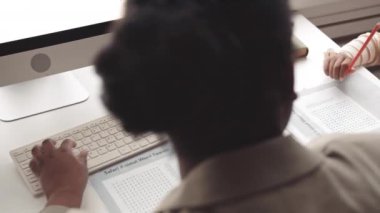 Orta ölçekli Afrika kökenli Amerikalı kadın konuşma terapisti ve modern sınıf dersleri alan akıllı anaokulu kızıyla yakın çekim.