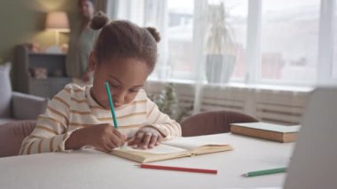 5 yaşındaki Afro-Amerikan bir kızın çizim defterinde rahat bir oturma odasında oturup annesiyle boş zamanlarını geçirmesi.