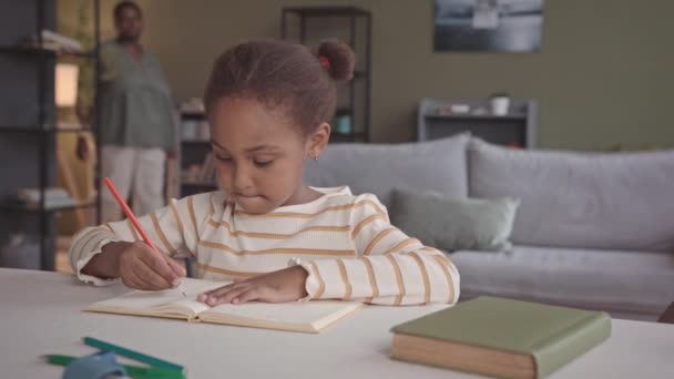 ウエストアップSlommoのスマートGen Aアフリカ系アメリカ人の女の子のために準備学校で彼女の思いやりのある母親と一緒に家で勉強 適切な文章を練習コピーブック — ストック動画