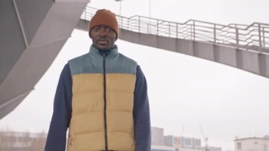 Ilık aktif giyimli özgüvenli Afro-Amerikalı adamın orta karar POV yavaşlaması kameraya bakıp sporun faydalarından bahsediyor ve soğuk sonbahar sabahında dışarıda koşuyor.