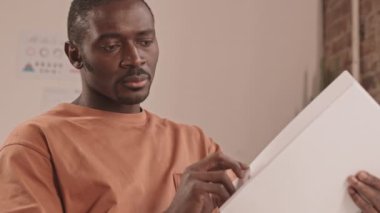 Ciddi bir Afro-Amerikan iş adamının beline dikkat et. Çatı katı tarzı bir ofiste oturmadan önce sayfalar dolusu iş sözleşmesine göz gezdir.