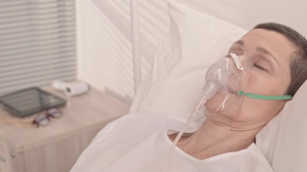 Panクローズアップとともに成熟した白人女性で酸素マスク睡眠で病院のベッド — ストック動画