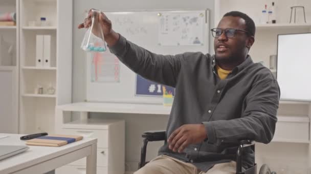 Foto Media Del Profesor Afroamericano Química Silla Ruedas Mostrando Frasco — Vídeos de Stock