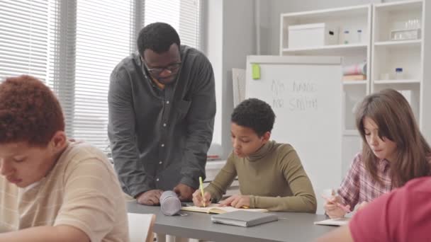Medium Slowmo African American Male Teacher Helping Female Pupil Sitting — Stock video