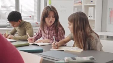 Modern sınıflarda yan yana oturan ilkokul kızlarının konuşmalarını yavaş yavaş bele al.