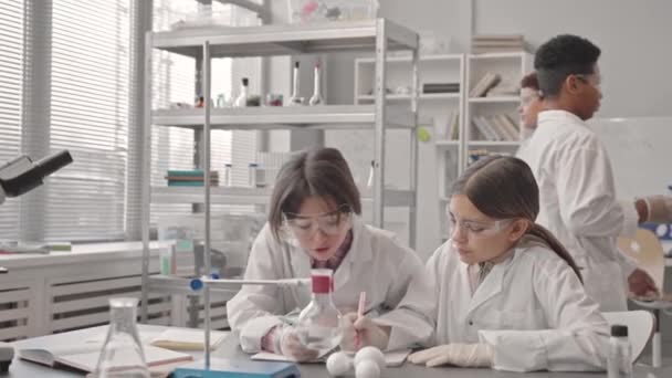 Lentitud Media Dos Colegialas Caucásicas Con Batas Laboratorio Gafas Protectoras — Vídeos de Stock