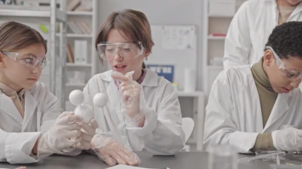 研究室のコートに身を包んだ多民族中学生や科学実験や科学教室での分子議論を行う保護眼鏡のパンウエストアップ — ストック動画