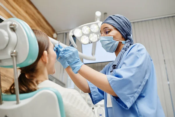 Dentista feminina examinando paciente na clínica — Fotografia de Stock