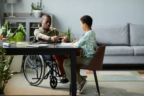 휠체어에 앉아 딸의 숙제를 도와 주는 흑인 남자 — 스톡 사진