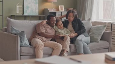 Modern ırklar arası çiftlerin yavaşı ve onların sevimli 8 yaşındaki kızları rahat bir oturma odasında oturmuş kitap okuyor, evde kilitli kalırken birlikte vakit geçiriyorlar.