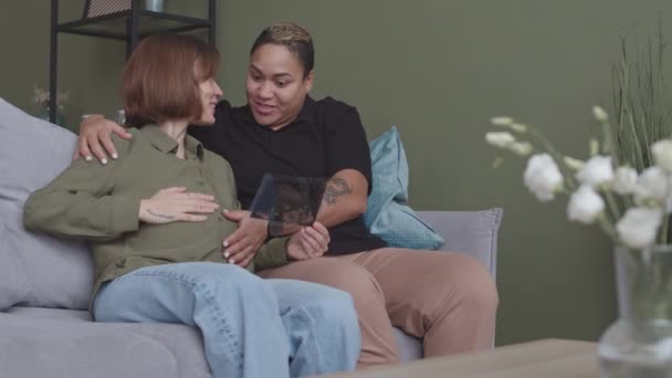 Medium Slowmo Interracial Forkælet Kvinder Venter Baby Sidder Sofaen Derhjemme – Stock-video