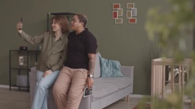 Hamile, ırklar arası lezbiyen bir çiftin rahat oturma odasında bebek ultrasonu ile selfie çekerken yavaş çekimleri.