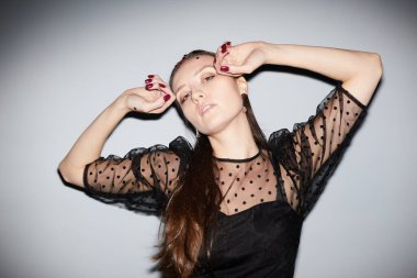 Partide gri arka planda dans eden genç bir kadının belden yukarı portresi.