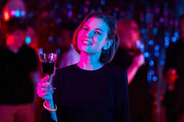 ウエストアップの肖像画の笑顔若い女性保持ドリンクパーティーでネオンライト コピースペース — ストック写真