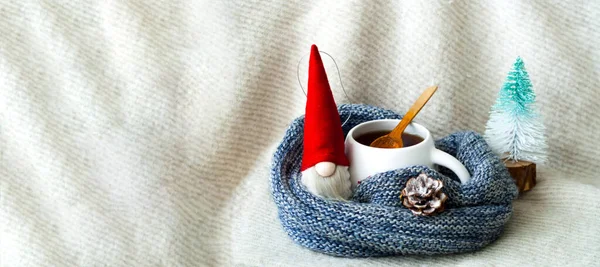 Juguete de Navidad Santa Claus y taza blanca con té en textura de punto. Tarjeta de felicitación navideña. Espacio de copia creativa. —  Fotos de Stock