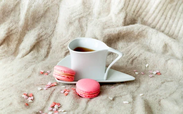 Chá branco e macaroons rosa na textura de malha. Pequeno-almoço acolhedor na Escandinávia. Cartão de Natal ou Dia dos Namorados. Espaço de cópia criativa. — Fotografia de Stock