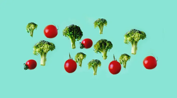 Creative vegetable background with flying broccoli and tomato on green background. The concept of healthy diet. Close-up — Stock Photo, Image