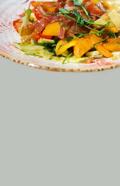 Delicate salad with ripe peach, cherry tomatoes, prosciutto, Parmesan cheese and honey-mustard sauce. Summer Color Trends, Attention-grabbing Palettes. Close-up.
