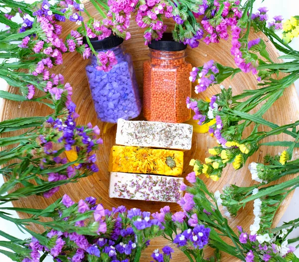 Bath Accessories against the background of kermek flowers. Daily bodycare concept, handmade organic bath products. Close-up, top view. 