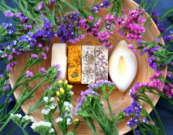 Handmade soap against the background of kermek flowers. Handmade organic soap concept from natural ingredients. Close-up, top view. 