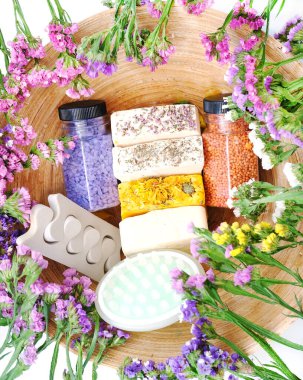 Bath Accessories against the background of kermek flowers. Daily bodycare concept, handmade organic bath products on bamboo texture. Close-up, top view. 