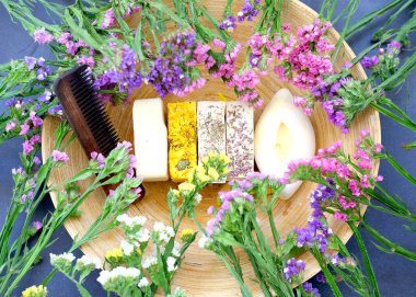 Handmade soap against the background of kermek flowers on bamboo texture. Handmade organic soap concept from natural ingredients. Close-up, top view. 