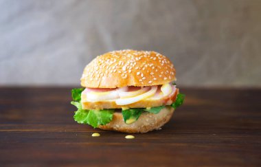 Sandwich with bacon and onion on semmel roll served on texture of old newspaper on rustic background. Bavarian snack the leberkaes semmel. Creative space for Sandwich Day design. Close-up 