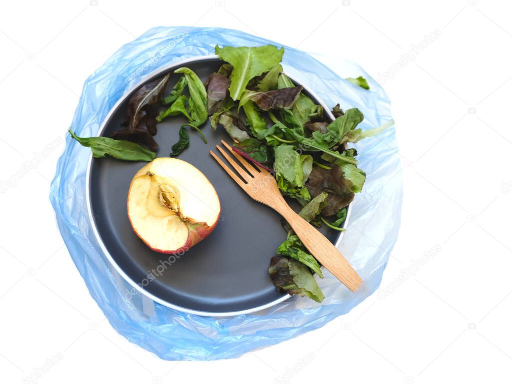 Blue plate with food waste in garbage bag. Food waste at home. The concept of the problem of the world food crisis. 