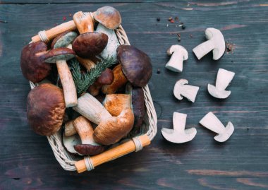 Tahta arka planda hasır kasede farklı taze mantarlar. Autumn Cep Mantarları. Organik gıda mantarı kavramı. 