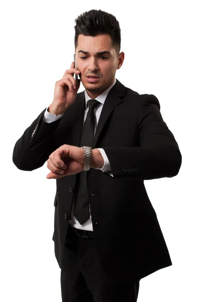 Empresário falando ao telefone e olhando para seu relógio — Fotografia de Stock