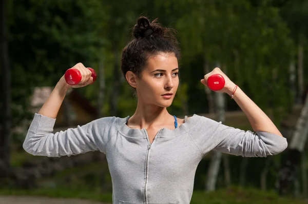 Beautiful woman holding weights in her hands — Stock Photo, Image