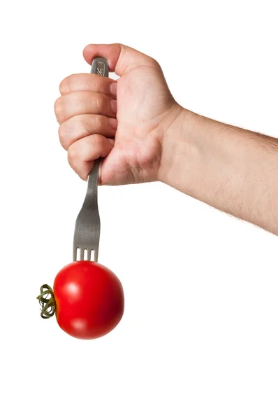 Uma mão atirando um garfo em um tomate vermelho — Fotografia de Stock