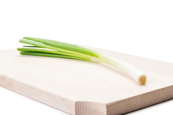 One spring onion on a wooden plat — Stock Photo, Image