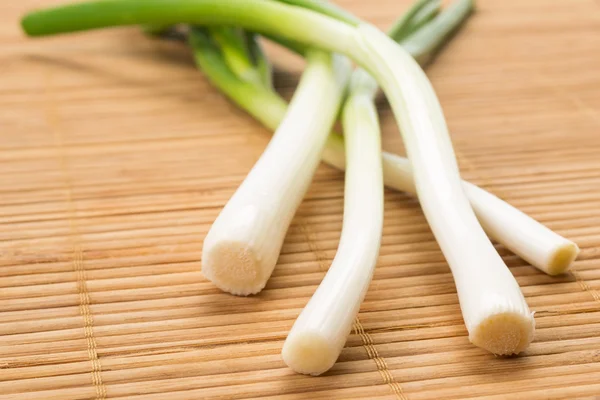 Bund grüner Frühlingszwiebeln auf einem hölzernen Hintergrund — Stockfoto