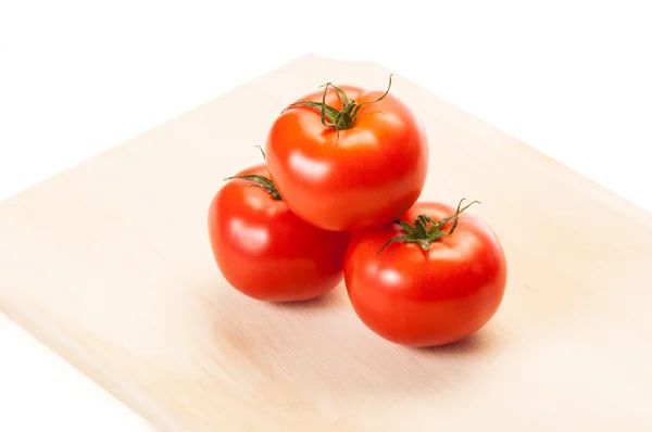 Drei rote Tomaten auf hölzernem Wildschwein — Stockfoto