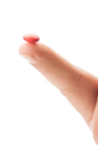 Closeup of one red pill on a finge Stock Photo
