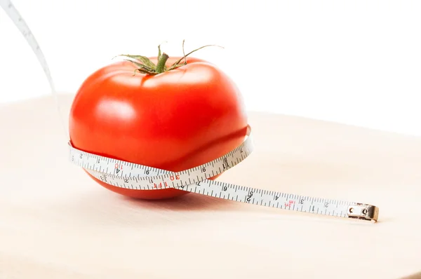 Mät kalorier i en röd tomat med en centimeter. kost koncept — Stockfoto