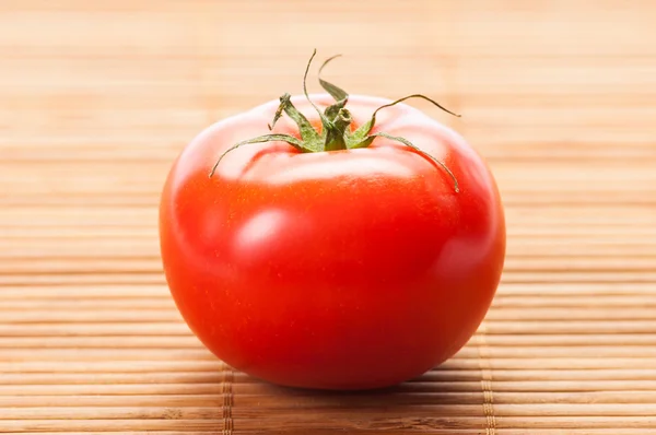 Perfekte rote Tomate auf Bambus-Tisch — Stockfoto