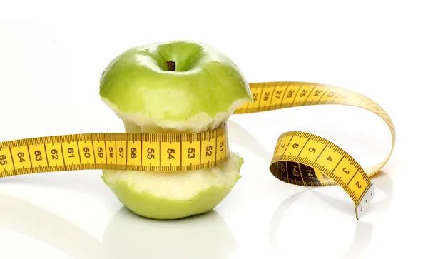 Comer manzana verde y una cinta métrica aislada —  Fotos de Stock