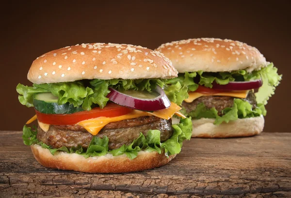 Ahşap zemin üzerinde iki lezzetli hamburger. — Stok fotoğraf