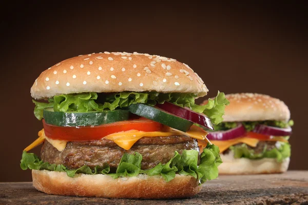 Twee heerlijke hamburgers op hout achtergrond. — Stockfoto